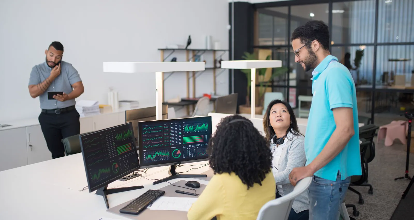 A team reviewing financial analytics together on desk monitors
