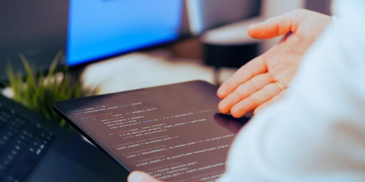 An engineer reviewing neural network code on a tablet at their desk